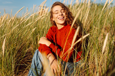 Beauty woman enjoying nature outdoors in grass. Calmness and tranquility. Travel, tourism concept.の写真素材