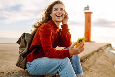 Young woman enjoying nature by the waterfront during a cloudy day by a lighthouse. Blogging conceptの写真素材