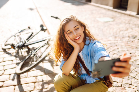 Selfie time. Happy woman using mobile phone while walking with a bicycle. Lifestyle.の写真素材