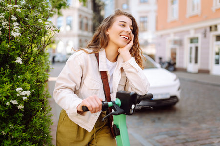 Happy woman rides an electric scooter in the city street on a sunny day. Ecological transport.の写真素材