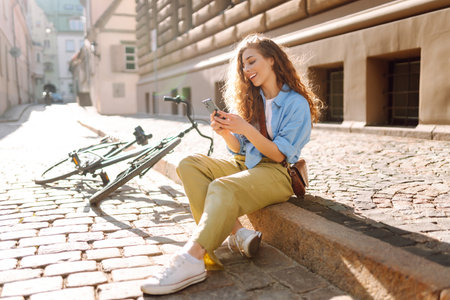Selfie time. Happy woman using mobile phone while walking with a bicycle. Lifestyle.の写真素材