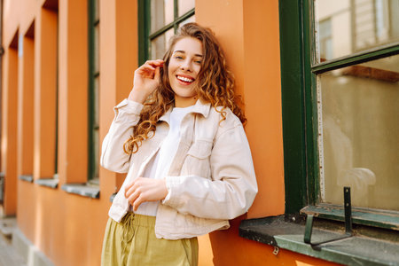 Optimistic woman with curly hair walking on the street city. Concept of lifestyle, fashion, travel.の写真素材