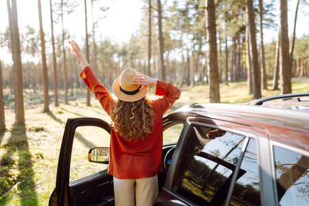 Stopping during a car trip. Young woman enjoying nature. Journey by car. Lifestyle, travel, tourismの写真素材