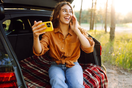 Happy Woman is resting in trunk of car and taking selfie. Selfie time. Lifestyle, travelの写真素材
