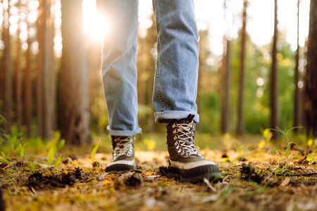 Feet of an adult wearing boots to travel walking in the forest. Feet walking in outdoor natureの写真素材