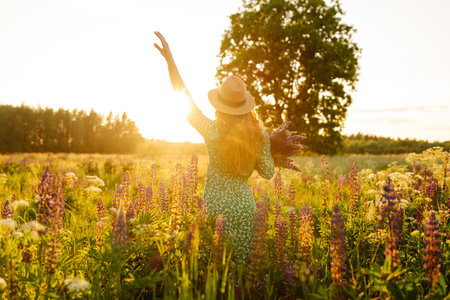 Stylish woman in a straw hat with a bouquet of flowers on a field with lupins. Lifestyle concept.の写真素材