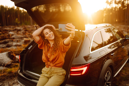 A woman in the trunk of a car at sunset. Traveling by car, camping. Active lifestyle.の写真素材