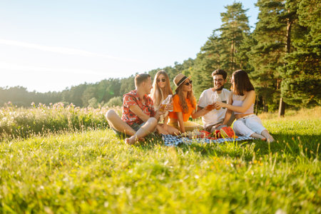 Happy group of friends resting in nature in picnic. People, lifestyle, relaxation, vacations concept.の写真素材