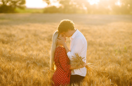 Young happy couple hugging on a wheat field, on the sunset. Enjoying time together.の写真素材
