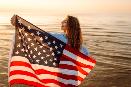 Young woman with American flag on beach. Patriotic holiday. Independence Day conceptの写真素材