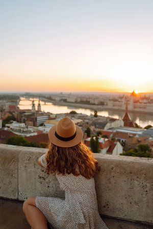 Portrait of happy woman tourist in hat at dawn enjoys cityscape. concept of an active lifestyle.の写真素材
