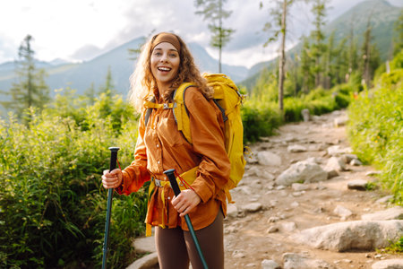 Young woman traveler hiking poles on trail among the mountains. Hiking. Active lifestyle.の写真素材