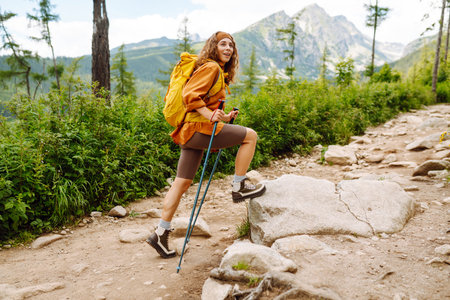 Young woman traveler hiking poles on trail among the mountains. Hiking. Active lifestyle.の写真素材