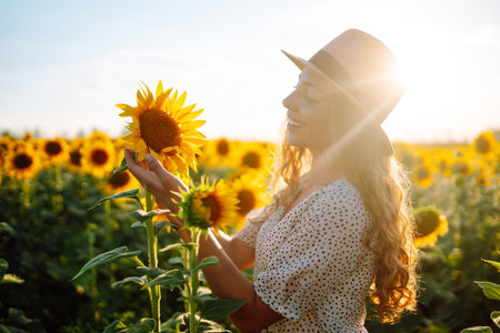 Happy young woman surrounded by yellow sunflowers in full bloom, traveling on holiday.の写真素材