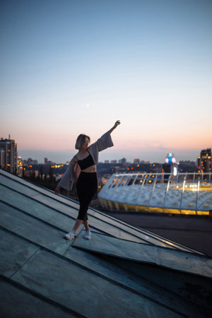 Beautiful woman on rooftop posing at sunset. Woman enjoys atmosphere of city of freedom. Relaxation.の写真素材