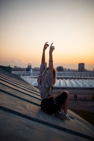 Beautiful woman on rooftop posing at sunset. Woman enjoys atmosphere of city of freedom. Relaxation.の写真素材