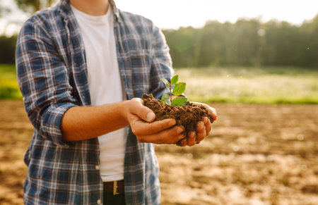 Man in a shirt holds a green plant in his hands. Caring for the environment.の写真素材