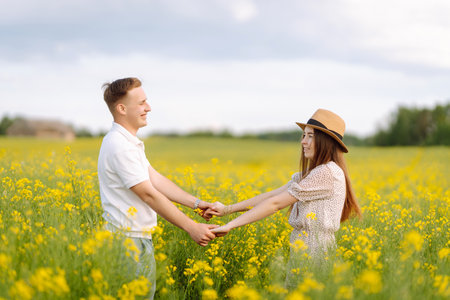 Young couple in love walks through a rapeseed field. The concept of love, test, relationship.の写真素材