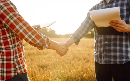 Handshake, joint work of farmers. Two farmers making agreement with handshake in wheat field.