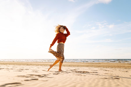 Stylish woman walks at sunset along beach of sea on at sunset. Travel, relax and lifestyle concept.の写真素材