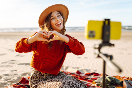 Happy woman using smartphone with stabilizer, live video in on sea beach. Live session blogging.の写真素材