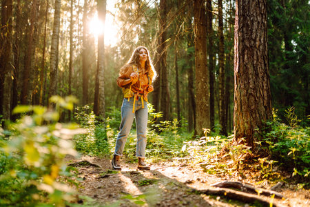 Stylish female looks for pathway among trees.の写真素材