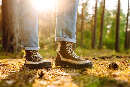 Feet of an adult wearing boots to travel walking in the forest. Feet walking in outdoor nature