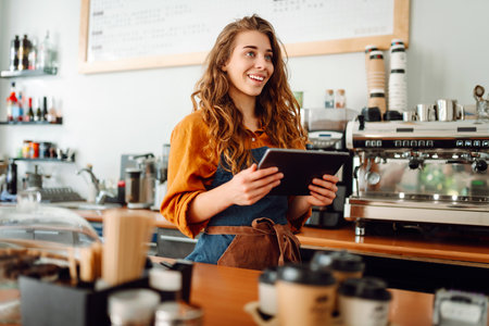 Beautiful woman owner stands behind the counter of a coffee shop. Business concept. Takeaway food.の写真素材
