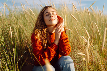Beauty woman enjoying nature outdoors in grass. Calmness and tranquility. Travel, tourism concept.