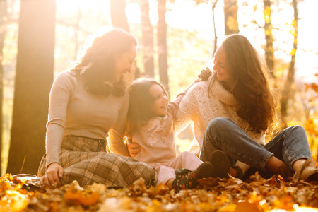The homosexual family playing with her daughter in the autumn forest. The adventure is more fun.