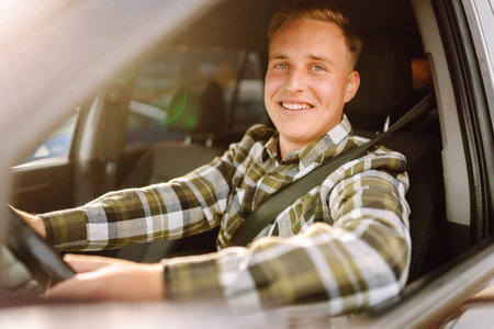 Portrait of handsome young man sitting in the driving seat of his car. Car travel, lifestyle concept