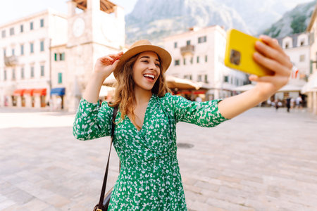 Happy woman takes a selfie photo on smartphone against the background of old city. Travel and lifeの写真素材