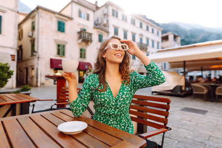 Young woman enjoying coffee at a cozy outdoor cafの写真素材