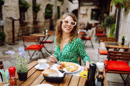Portrait of a smiling woman eating at cozy restaurant outdoors.の写真素材
