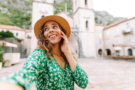 Beautiful woman walks the streets and takes selfie using smartphone camera. Blogging, lifestyleの写真素材