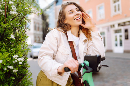 Beautiful woman riding an electric scooter. Street-style, Ecological transport. Active lifestyle.の写真素材