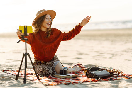 Happy woman using smartphone with stabilizer, live video in on sea beach. Live session blogging.の写真素材