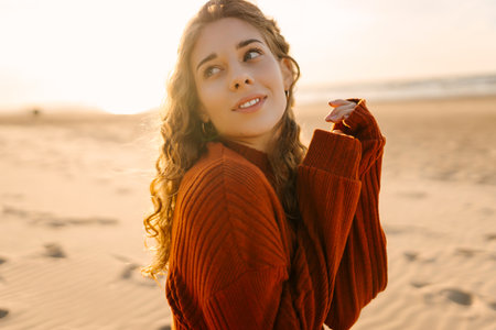 Portrait of a beautiful woman on the beach at sunset. Girl walks along the beach and enjoys weatherの写真素材