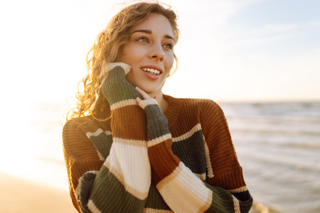 Portrait of a beautiful woman on the beach at sunset. Girl walks along the beach and enjoys weatherの写真素材