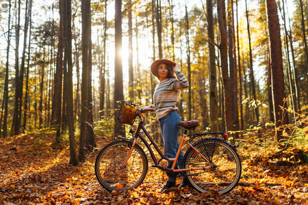 Happy active young woman on bike in autumn park at sunset. Concept of people, recreation, active lifestyle.の写真素材