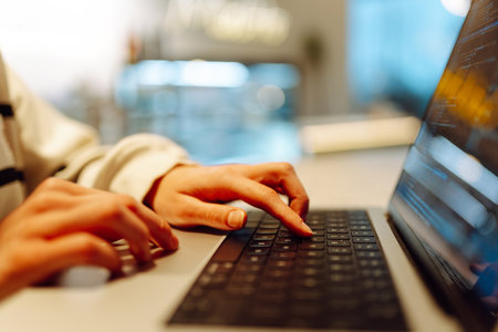 A young woman is engaged in typing on a laptop.