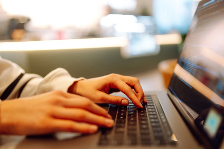 A young woman is engaged in typing on a laptop.
