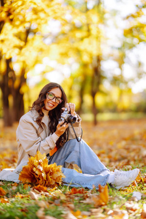 Beautiful woman taking pictures in the autumn forest. Rest, relaxation, tourism, lifestyle concept.の写真素材