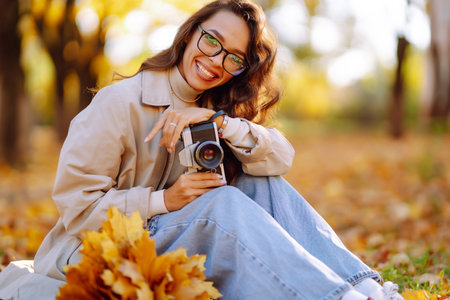 Beautiful woman taking pictures in the autumn forest. Rest, relaxation, tourism, lifestyle concept.の写真素材