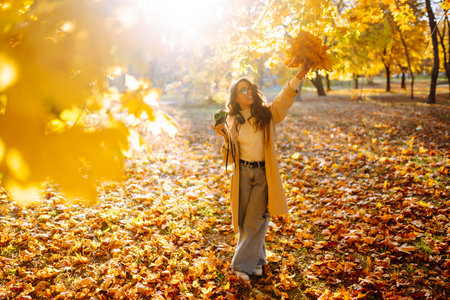 Young woman taking pictures in the autumn forest. Lady Walking In Fall Park With Yellow Foliage.の写真素材