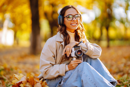Beautiful woman taking pictures in the autumn forest. Rest, relaxation, tourism, lifestyle concept.の写真素材