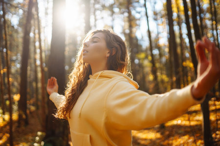 Beautiful woman practices yoga in the autumn forest. Lifestyle and meditation concept.の写真素材