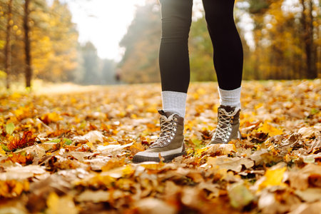 Female legs in boots walking through fallen trees in autumn park. Nature, travel concept.
