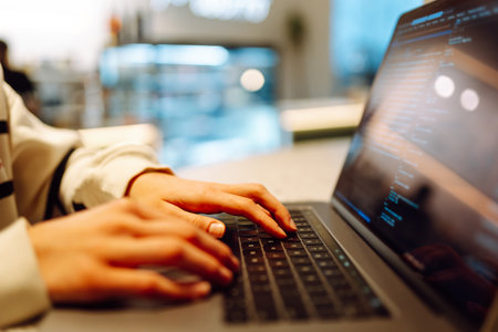 A young woman is engaged in typing on a laptop.
