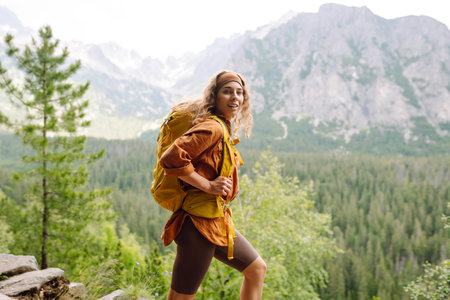 Smiling traveler with a bright backpack on a hiking mountain trail. Active lifestyle.の写真素材